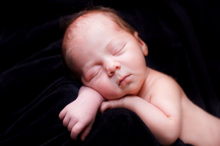 Newborn girl sleeps on black velvet