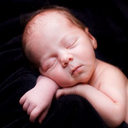 Newborn girl sleeps on black velvet